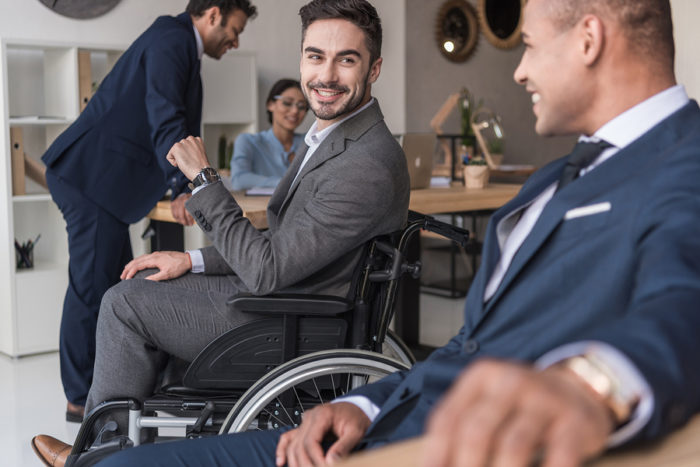 selective focus of smiling disabled businessman and colleagues in office
